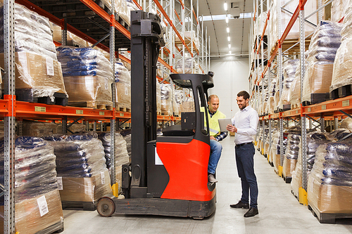 wholesale, logistic, loading, shipment and people concept - loader on forklift and businessman with tablet pc computer at warehouse