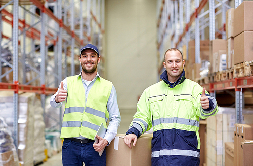 logistic, delivery, shipment, people and export concept - happy men or manual workers with boxes showing thumbs up at warehouse