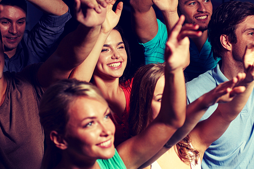 party, holidays, celebration, nightlife and people concept - smiling friends waving hands at concert in club