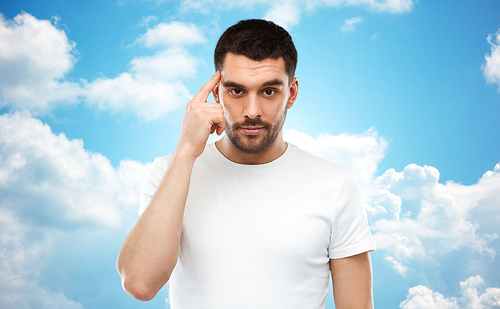 advertisement, idea, mind and people concept - man pointing finger to his temple over blue sky and clouds background