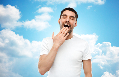 rest, bedtime and people concept - tired yawning man over blue sky and clouds background