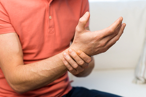 people, healthcare and problem concept - close up of man suffering from pain in hand oe wrist at home