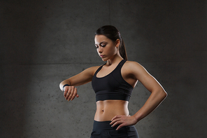 sport, fitness, technology and people concept - young woman with heart-rate watch in gym