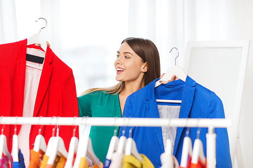 clothing, fashion, style and people concept - happy woman choosing clothes at home wardrobe