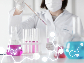 science, chemistry, biology, medicine and people concept - close up of young female scientist with pipette and flask making test or research in clinical laboratory