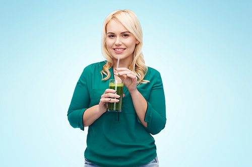 healthy eating, vegetarian food, diet, detox and people concept - smiling young woman drinking green vegetable juice or smoothie from glass over blue background
