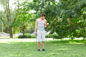 fitness, sport, exercising, training and lifestyle concept - young man exercising with expander in summer park