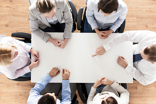 business, people and team work concept - close up of creative team sitting at table and pointing finger to something in office