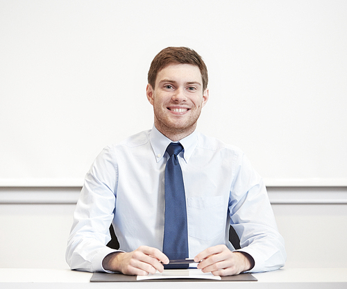 business, people and work concept - smiling businessman sitting in office in front of whiteboard