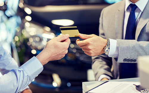 auto business, sale and people concept - close up of customer giving credit card to car dealer in auto show or salon