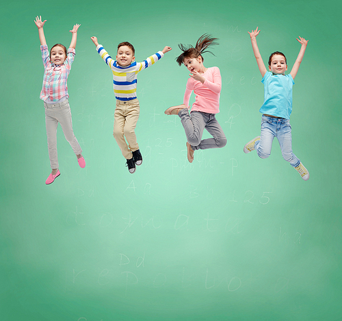 school, education, childhood, freedom and people concept - happy little girl jumping in air over green school chalk board background