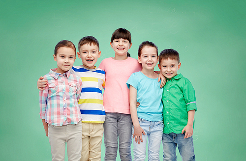 childhood, preschool education, friendship and people concept - group of happy smiling little children hugging over green school chalk board background