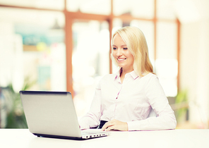 education, business and technology concept - smiling businesswoman or student with laptop computer over office room background