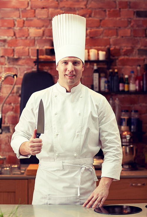 cooking, kitchenware and people concept - happy male chef cook with knife in restaurant kitchen