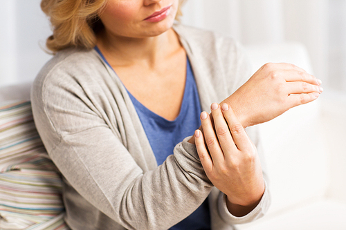 people, healthcare and problem concept - close up of woman suffering from pain in hand at home