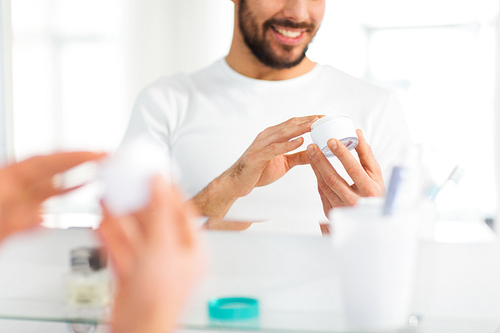 beauty, skin care and people concept - close up of happy young man with facial cream at bathroom