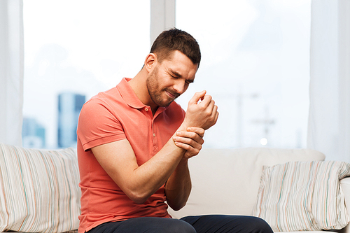 people, healthcare and problem concept - unhappy man suffering from pain in hand at home