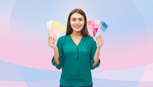 color scheme, decoration, design and people concept - smiling young woman with color swatches or samples over pink and violet background