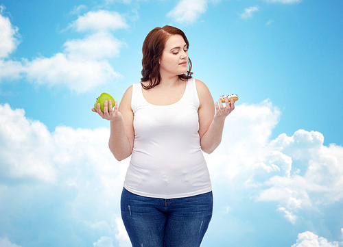 healthy eating, junk food, diet and choice people concept - plus size woman choosing between apple and cookie over blue sky and clouds background