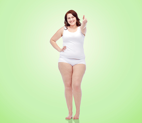 gesture, weight loss and people concept - smiling young plus size woman in underwear showing thumbs up over green natural background