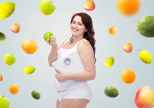 weight loss, diet, slimming, healthy eating and people concept - happy young plus size woman in underwear holding scales and green apple over gray background with fruits