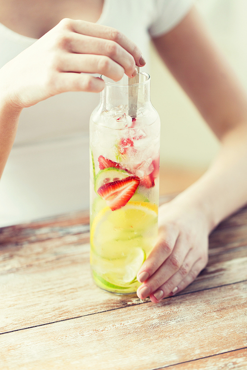 healthy eating, drinks, diet, detox and people concept - close up of woman with fruit water in glass bottle