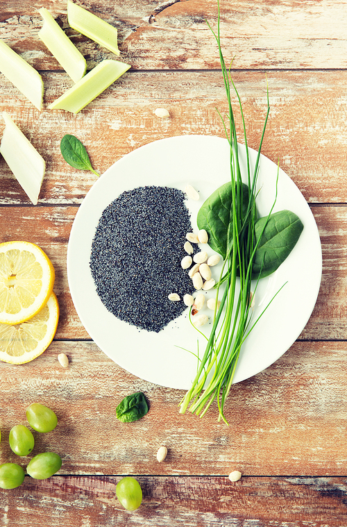 healthy eating, vegetarian super food, culinary and diet concept - close up of peeled peanuts, greens and poppy or chia seeds