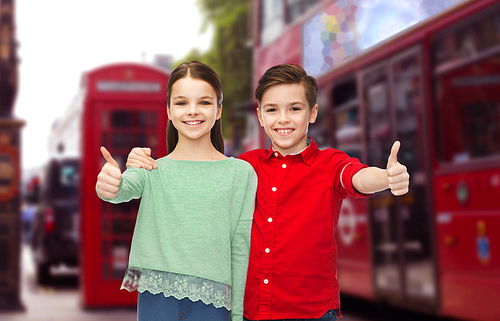 childhood, travel, tourism, gesture and people concept - happy smiling boy and girl hugging and showing thumbs up over london city street background