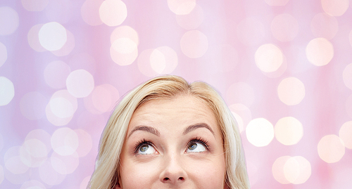 curiosity, advertisement and people concept - happy young woman or teenage girl face over pink holidays lights background