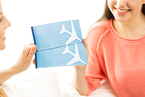 tourism, travel, vacation and people concept - close up of women with airplane tickets at home