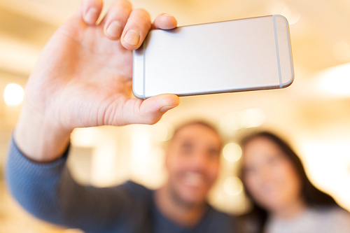 people, technology and dating concept - close up of happy couple taking smartphone selfie at cafe or restaurant