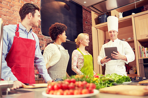 cooking class, culinary, food, technology and people concept - happy friends with tablet pc in kitchen