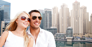 summer holidays, tourism, vacation, travel and dating concept - happy couple in shades over dubai city background