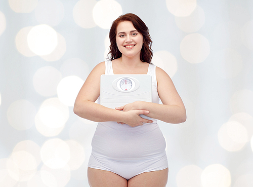 weight loss, diet, slimming, plus size and people concept - happy young plus size woman in underwear holding scales over holidays lights background