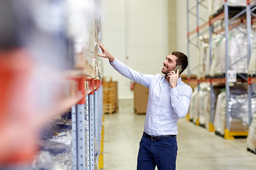 wholesale, logistic, business, export and people concept - smiling businessman calling on smartphone at warehouse