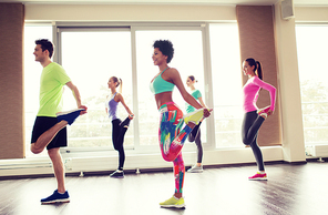 fitness, sport, training, gym and lifestyle concept - group of smiling people with trainer exercising and stretching in gym