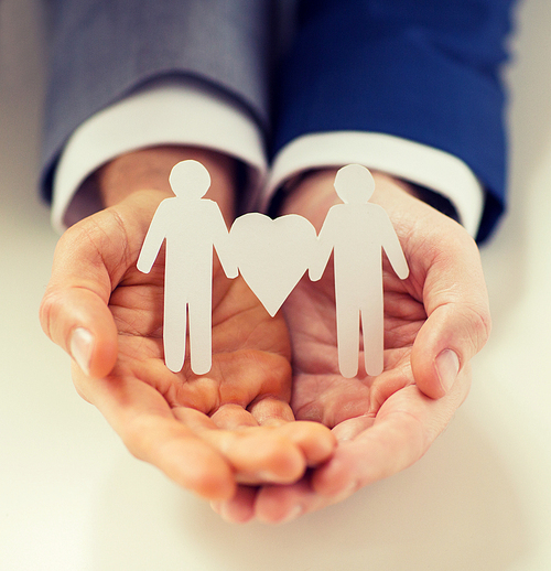 people, homosexuality, same-sex marriage and love concept - close up of happy male gay couple holding paper cutout love symbol