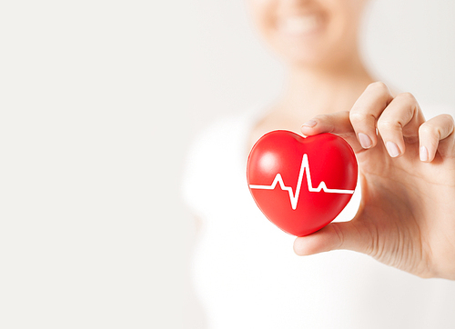 health, medicine, people and cardiology concept - close up of happy woman with cardiogram on small red heart
