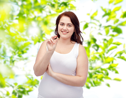 weight loss, diet, slimming, medicine and people concept - happy plus size woman in underwear with pill over green natural background