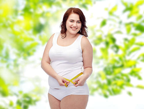 weight loss, diet, slimming, size and people concept - happy young plus size woman in underwear measuring tape over green natural background