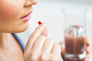 medicine, health care and people concept - close up of woman taking in pill
