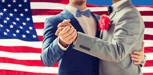 people, homosexuality, same-sex marriage and love concept - close up of happy male gay couple holding hands and dancing on wedding over american flag background