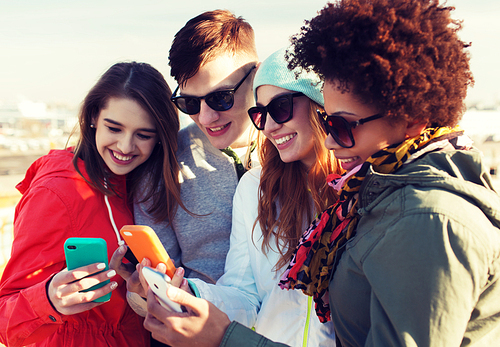 people, friendship, cloud computing and technology concept - group of smiling teenage friends with smartphone outdoors