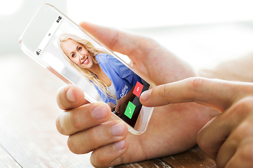 business, technology, communication and people concept - close up of male hand holding and showing transparent smartphone with incoming call from woman