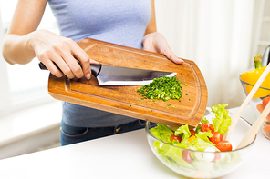 healthy eating, cooking, vegetarian food, diet and people concept - close up of woman adding chopped green onion to salad
