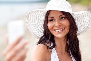 travel, leisure, summer, technology and people concept -  young woman taking selfie with smartphone on beach