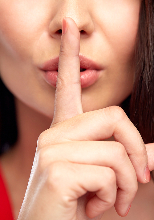 people, gesture, secret and silence concept - close up of woman face holding finger on her lips