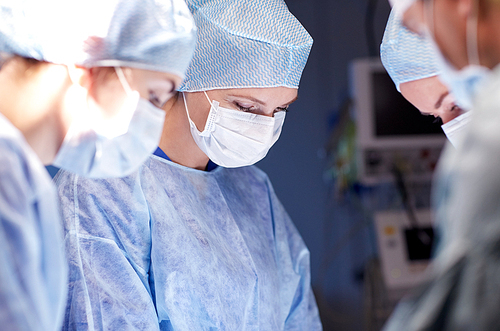 surgery, medicine and people concept - group of surgeons at operation in operating room at hospital