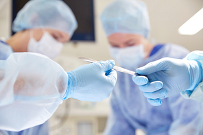 surgery, medicine and people concept - close up of surgeons hands with scalpel at operation in operating room at hospital