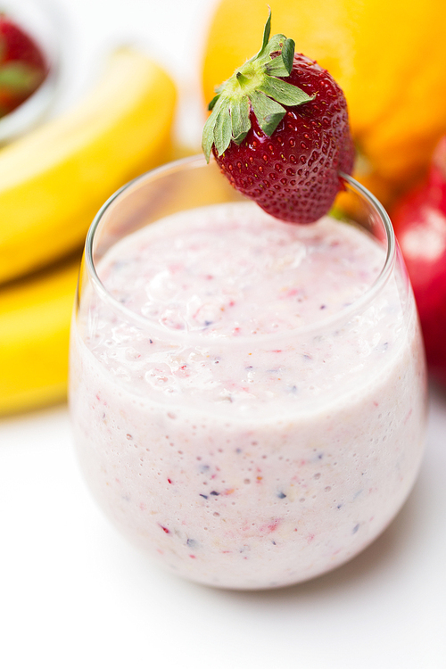 healthy eating, cooking, vegetarian food, ing and people concept - close up of glass with strawberry milk shake and fruits